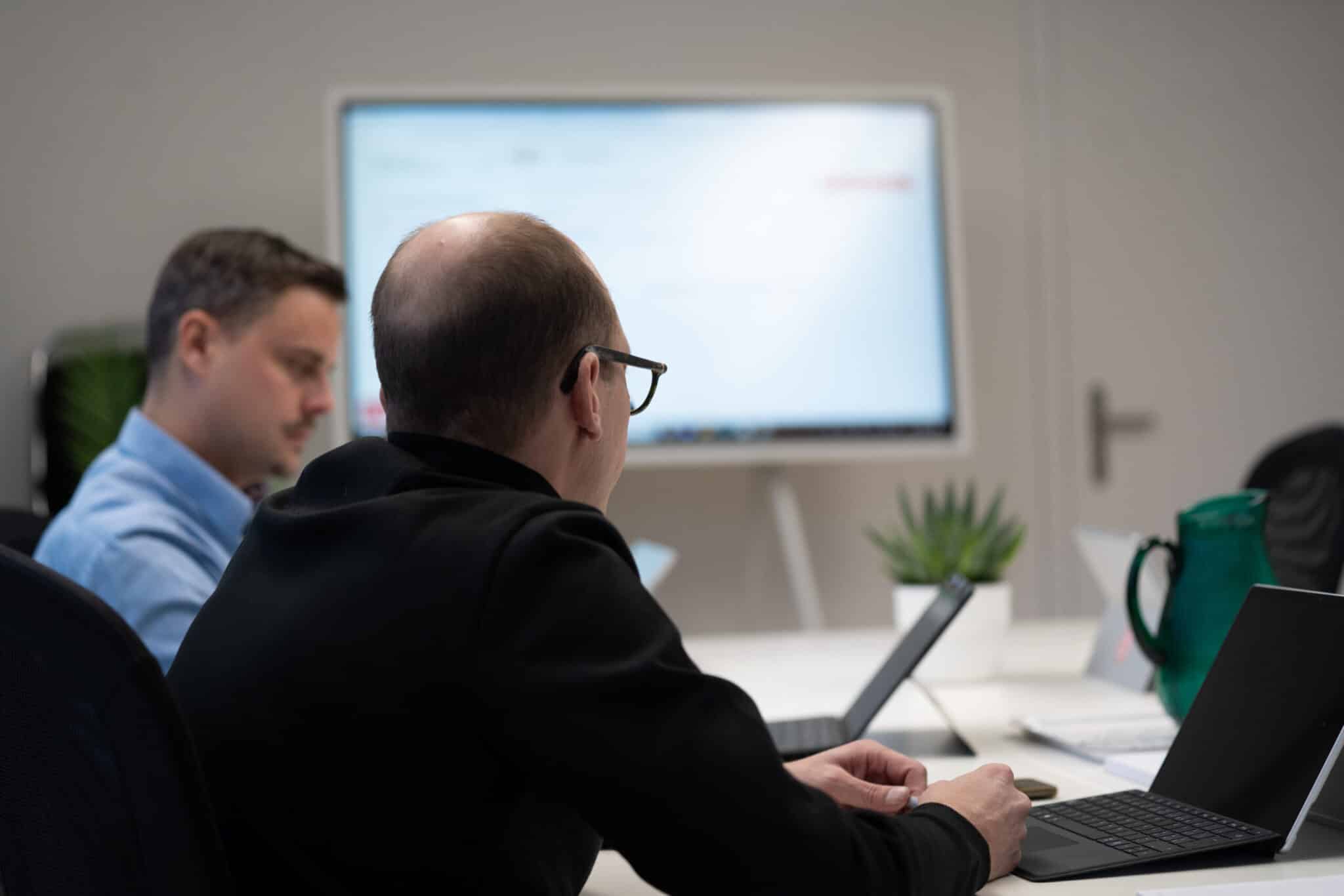 Two people in a meeting room working on laptops, representing jobs and careers at myls.